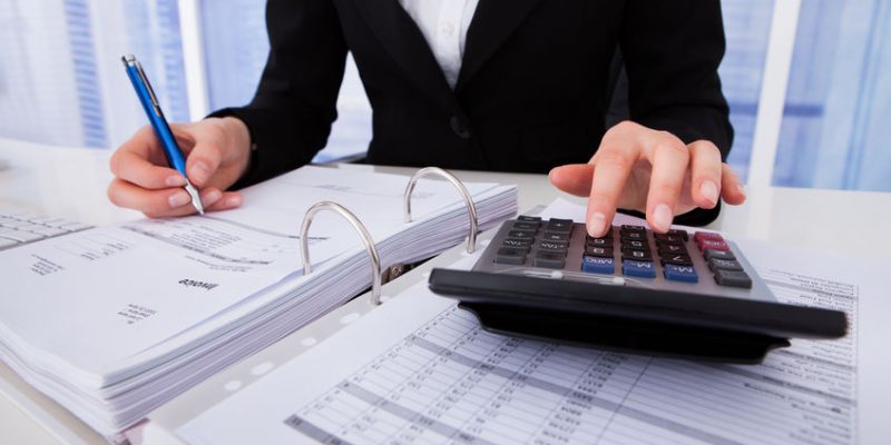 Midsection of businesswoman calculating tax at office desk